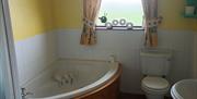 A bathroom with a walk-in shower, a corner bath, a toilet and a sink.