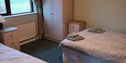 A bedroom with a double bed, a single bed, a wardrobe and a window.