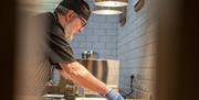 Chef bringing a tray of fresh potato breads to the hot plate part of the breakfast buffet.