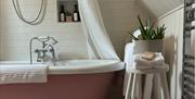 bathroom of the pink cottage with pink pattern floor tiles and pink bath
