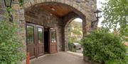 Hotel entrance under stone arches with an exit to a car park.