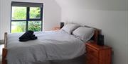 Double bedroom with folded towels and a window.