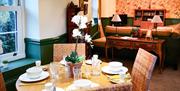 A dining room table set with glasses and crockery and archway leading to a sitting room.