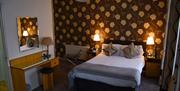 A double bedroom with brown flower wallpaper and a makeup desk.