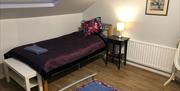 Bedroom with a purple bed, bedside table with lamp and picture on the wall.