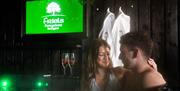 Couple in hot tub with 2 robes hanging in the background and 2 champagne glasses on the side.