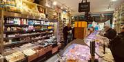 A deli packed with fresh food prepared behind the counter and packaged food in the fridge and on shelves.