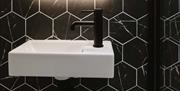 A sink in the bathroom of DB Stays 'The Cove' with an LED back-lit mirror above