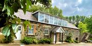 A renovated stone cottage with second floor windows.