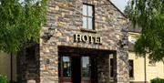A stone entrance to a hotel with a window and trees.
