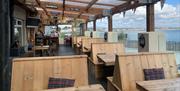 Outside dining area of The Harbour House Inn with wooden benches overlooking the stunning sea