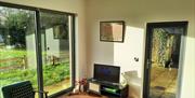 A living room with chairs, a coffee table, a TV, patio windows and a glass door.