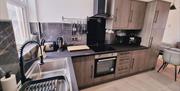 Kitchen with a sink, toaster, coffee maker, hob/oven and a selection of utensils.