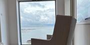 Image of chair placed at window with sea view