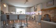 Large kitchen with a high table, chairs and a woodburning fireplace.