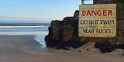 Sign at Portstewart Strand reads 'DANGER DO NOT SWIM NEAR ROCKS'