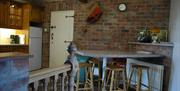 A kitchen dining room with a fridge, bench with stools and a door.