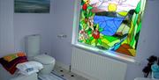 A bathroom with a bath, sink, toilet and a large stained-glass window.