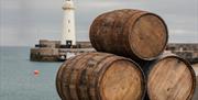 Three barrels stacked in a triangle on Donaghadee Pier with the lighthouse in the background