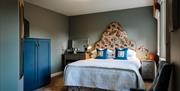 Image shows double bedroom with side table, dressing table and mirror.