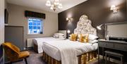 Image shows double bed and single bed in room with dressing table and mirror