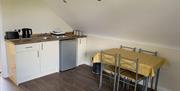 Image shows wooden floor kitchen area with dining table