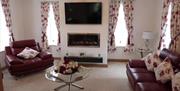 Sitting area with red suite, coffee table, fireplace, TV and windows.