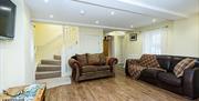 Image shows lounge with 2 sofas, coffee table, TV on wall and wooden flooring