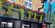 Exterior of Jack's Bar at Walsh's Hotel in Maghera, featuring a black facade with gold lettering that reads "Jack's Bar Wines & Spirits Est. 1760." Co