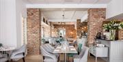 Image shows dining room with many tables and chairs