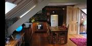 Image shows kitchen area with dining table, fridge and oven