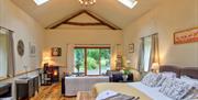A combination double bed/sitting room with a fireplace inside an open plan converted barn with patio doors.