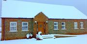 Image shows the front of the property with roof covered in snow and snow covered driveway