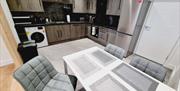 Kitchen area with a grey and silver colour theme and a grey table and chairs.