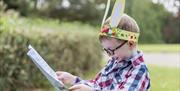 A young boy wearing bunny ears reading an Easter trail map
