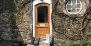 An image of the front of the accommodation with stone walls and round window to the right of the front door