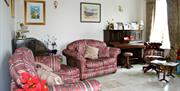 A tiled living room with two red sofas and a piano beside the window.