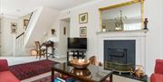 Living room with a coffee table, fireplace, TV, desk and a staircase.