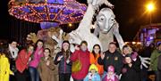 Image shows a group of people standing in front of scary Halloween characters, with a Fairground in the background