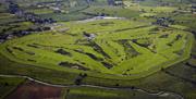 Shows aerial image of the whole golf course and surrounding countryside