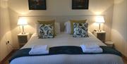 One of the apartments bedrooms with a double bed, bedside tables and folded towels.