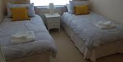 Bedroom with two single beds, a window, and fresh towels.