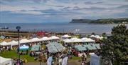 crowds of people browsing busy seaside market stalls