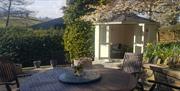 Outside seating area with garden furniture, a gazebo and a blossoming tree.