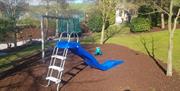 Childs play aera with a slide, swings, a trampoline and a bench.