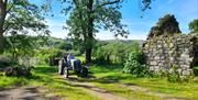 A vintage Ferguson tractor being driven past old stone cottage wall steads