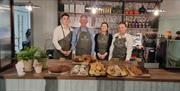 Staff from Bistro at the Courthouse stand behind the restaurants counter, with plenty of bakes and sweet treats in front of them