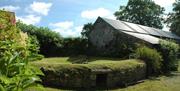 A garden with a raised stone wall, a barn and flowers.