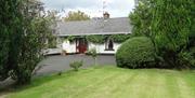 Outside of cottage, garden and trees in image