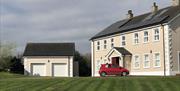 Image shows front of property with red car parked outside. Also detached double garage next to property